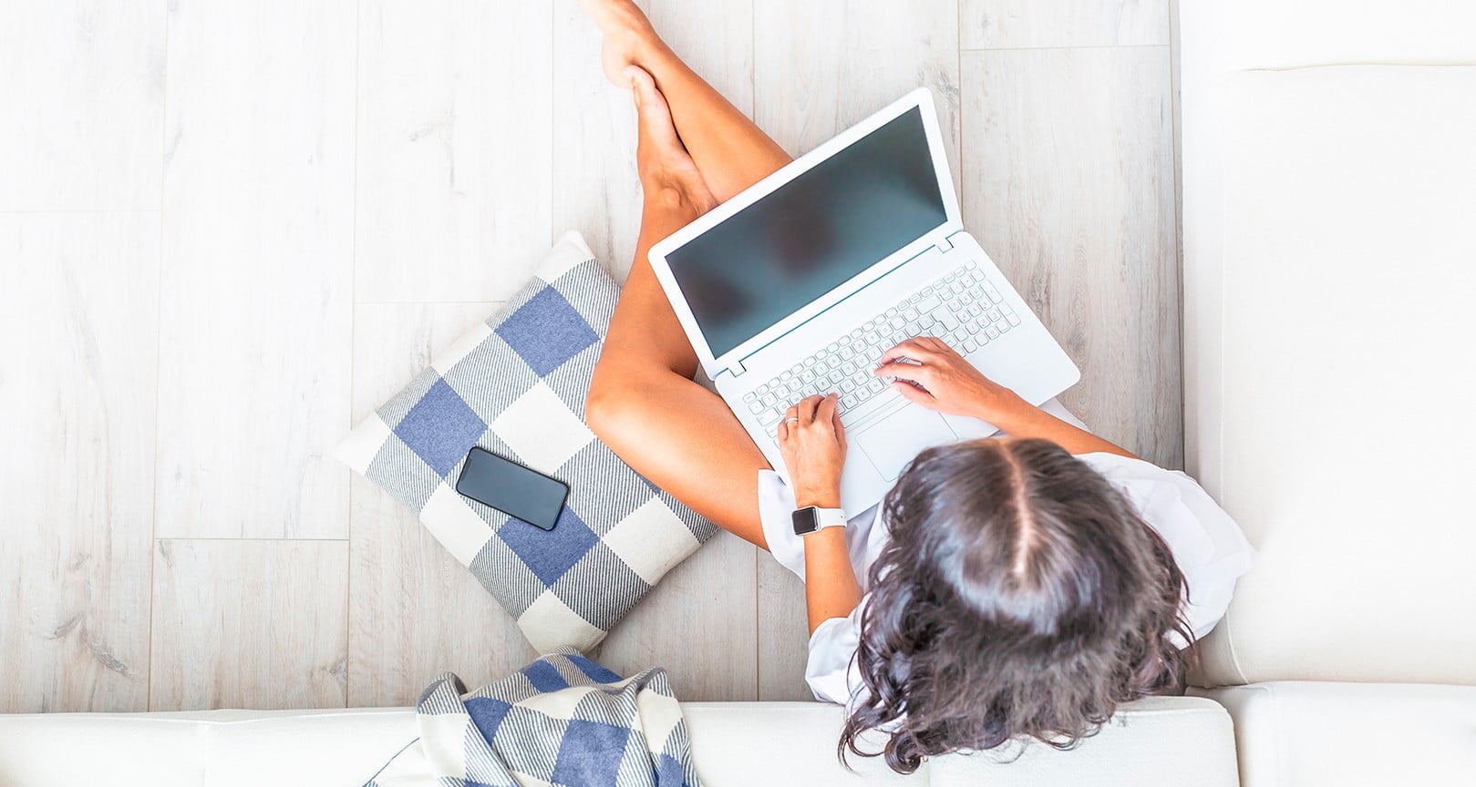 Nainen istuu lattialla ja kirjoittaa tietokoneella