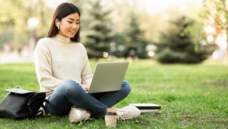 Avoin työhakemus: nuori nainen työskentelee tietokoneella puistossa